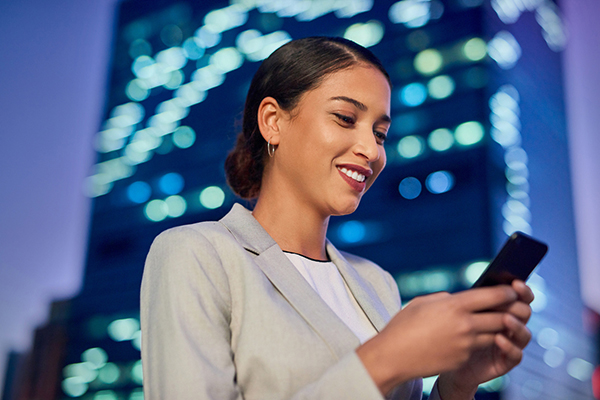 Woman looking at her phone beside a skyscraper