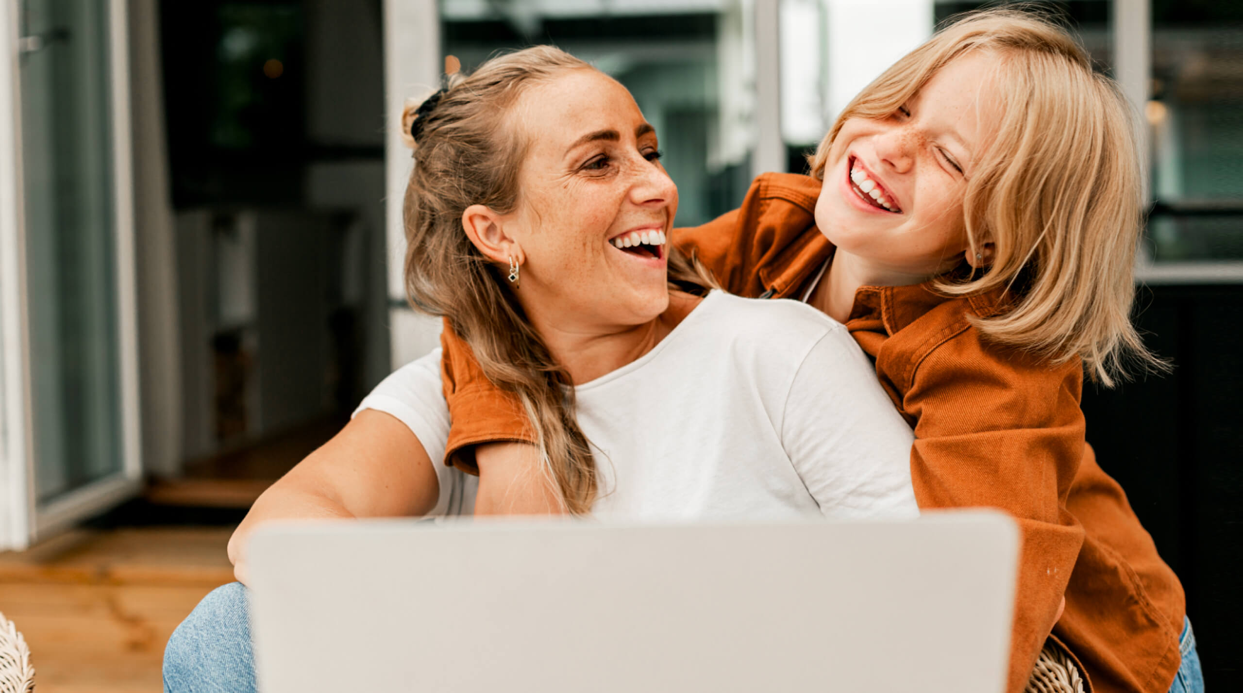 Woman smiling at child looking at laptop