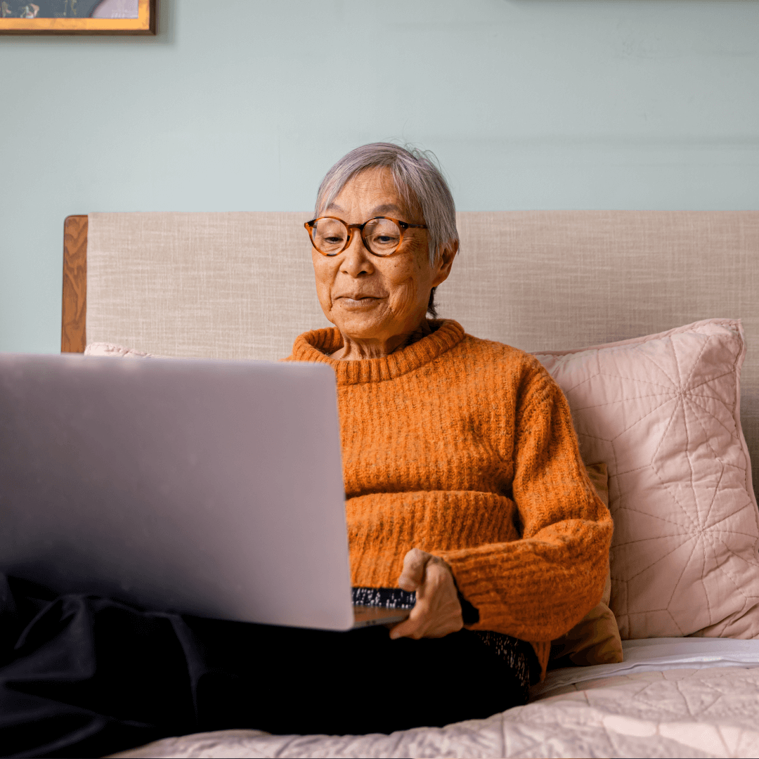 older woman on laptop from bed steps to smarter investing